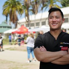 Richard Dang stands outside in his USC Pharmacy scrubs