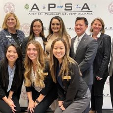 Group of students and pharmacy industry leaders in front of an APSA backdrop